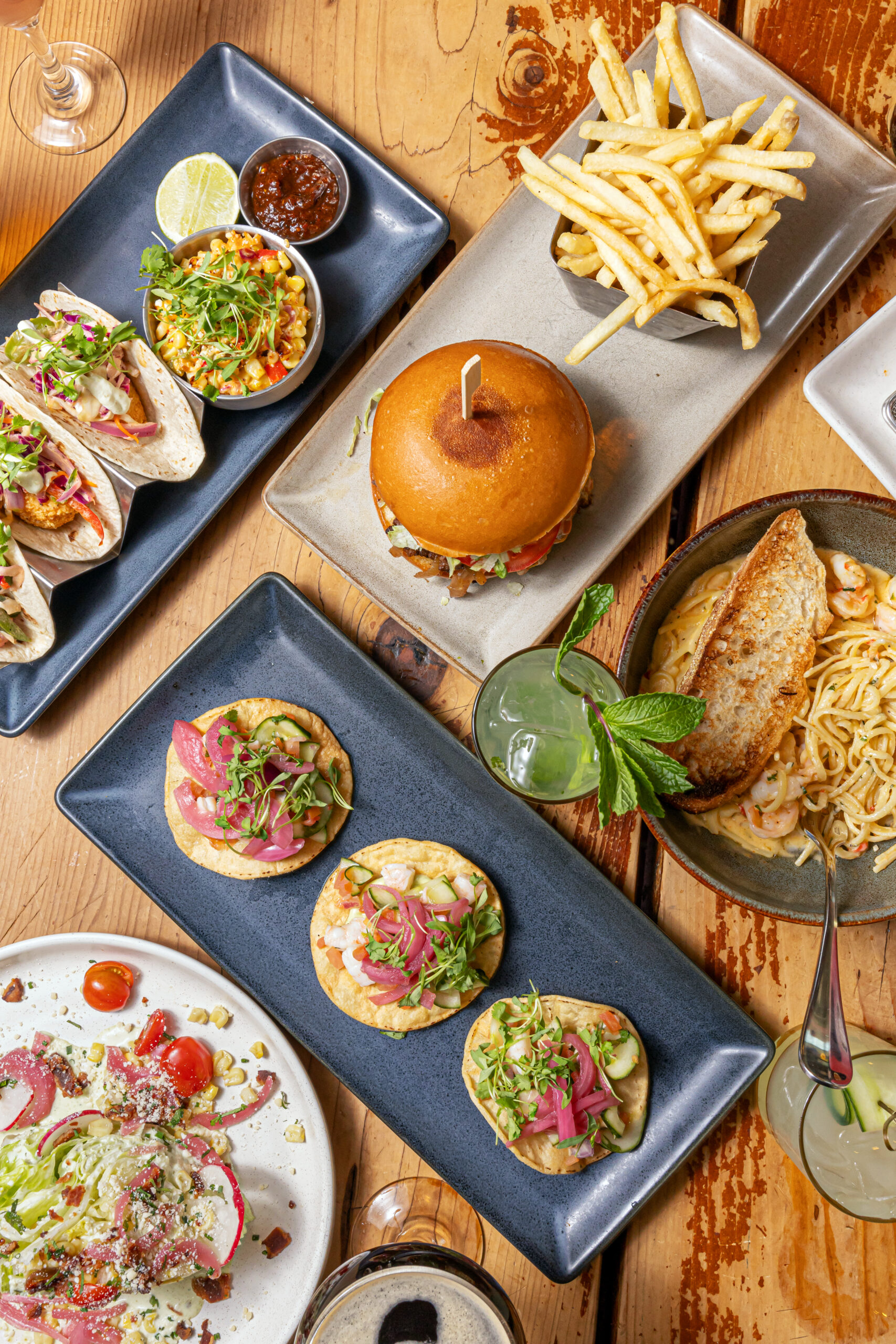 Shareable game day appetizers at Cafe Americano featuring spice-brined chicken wings, empanadas, and double smash burgers for the ultimate Super Bowl 2026 watch party