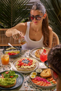 Full brunch spread featuring avocado toast, waffles and fresh juices on the Cafe Americano terrace, the best all day brunch Miami Beach spot